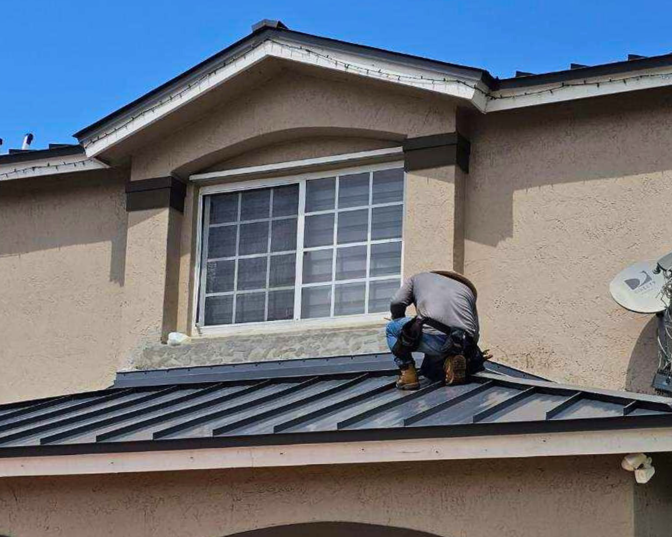 Professional roofing contractors installing a metal roof panel on a residential home